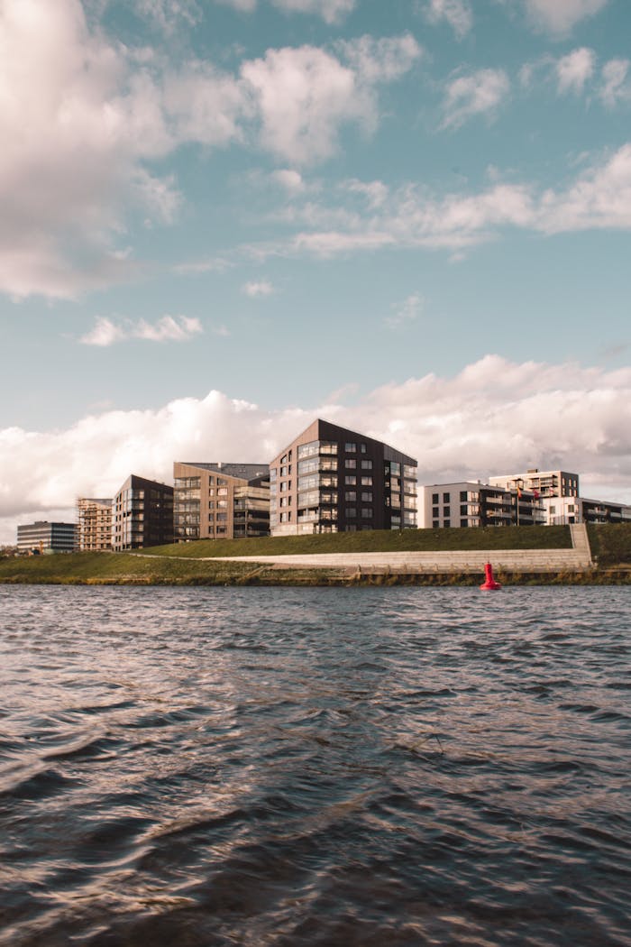 Modern residential architecture along the Klaipėda River under a bright sky.